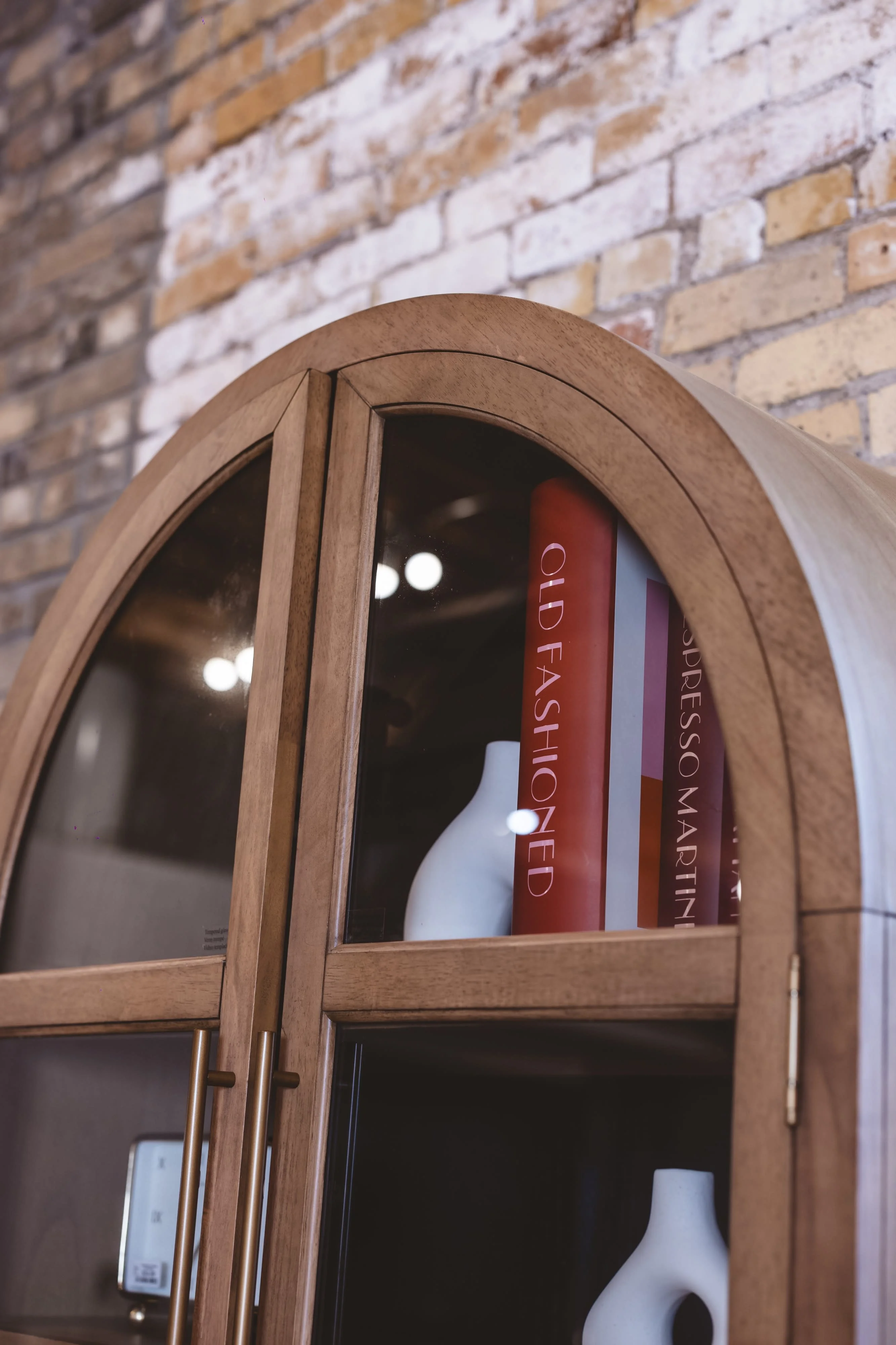 Arched wooden cabinet with vases against brick