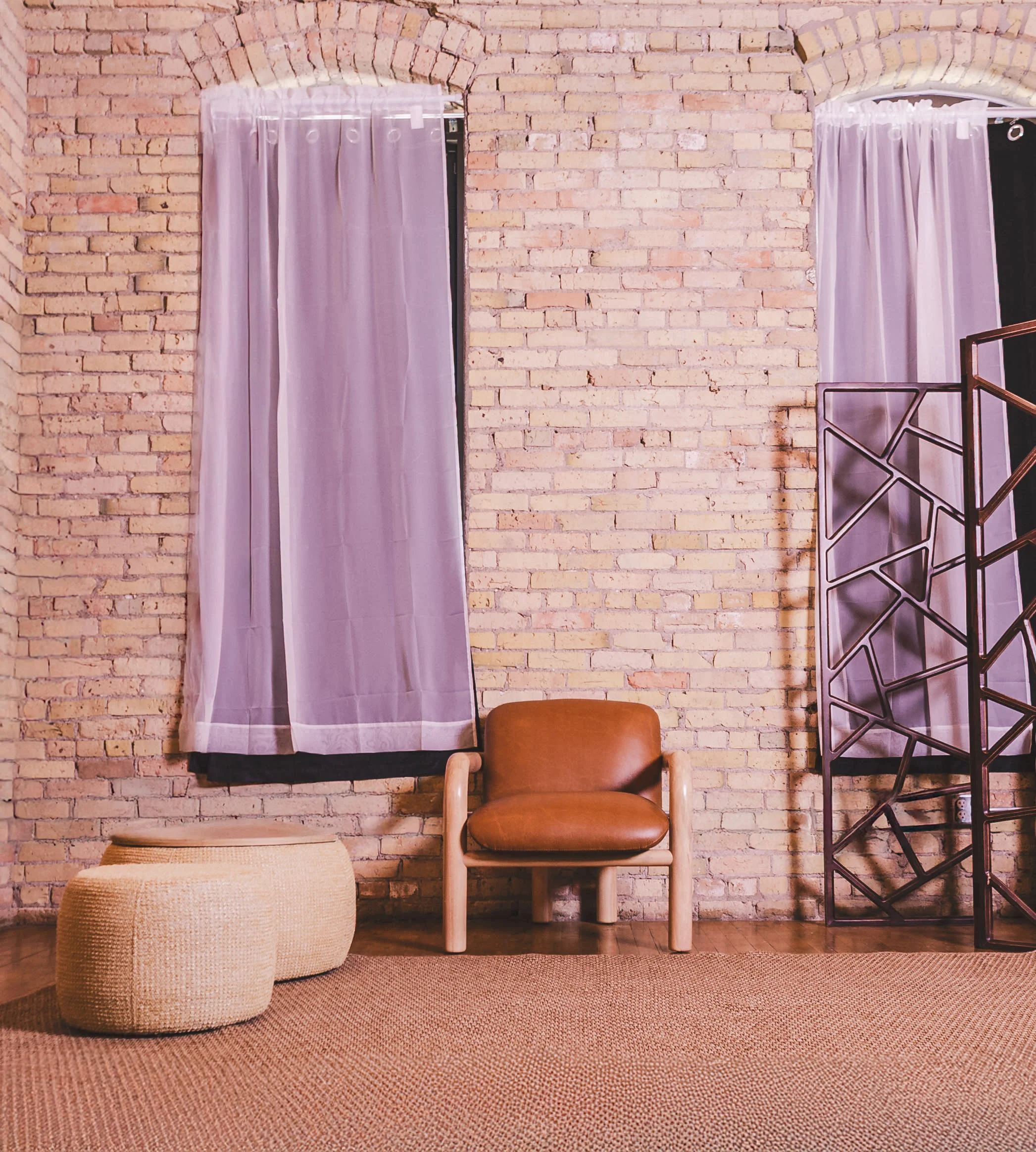 Leather chair and woven poufs in a brick corner