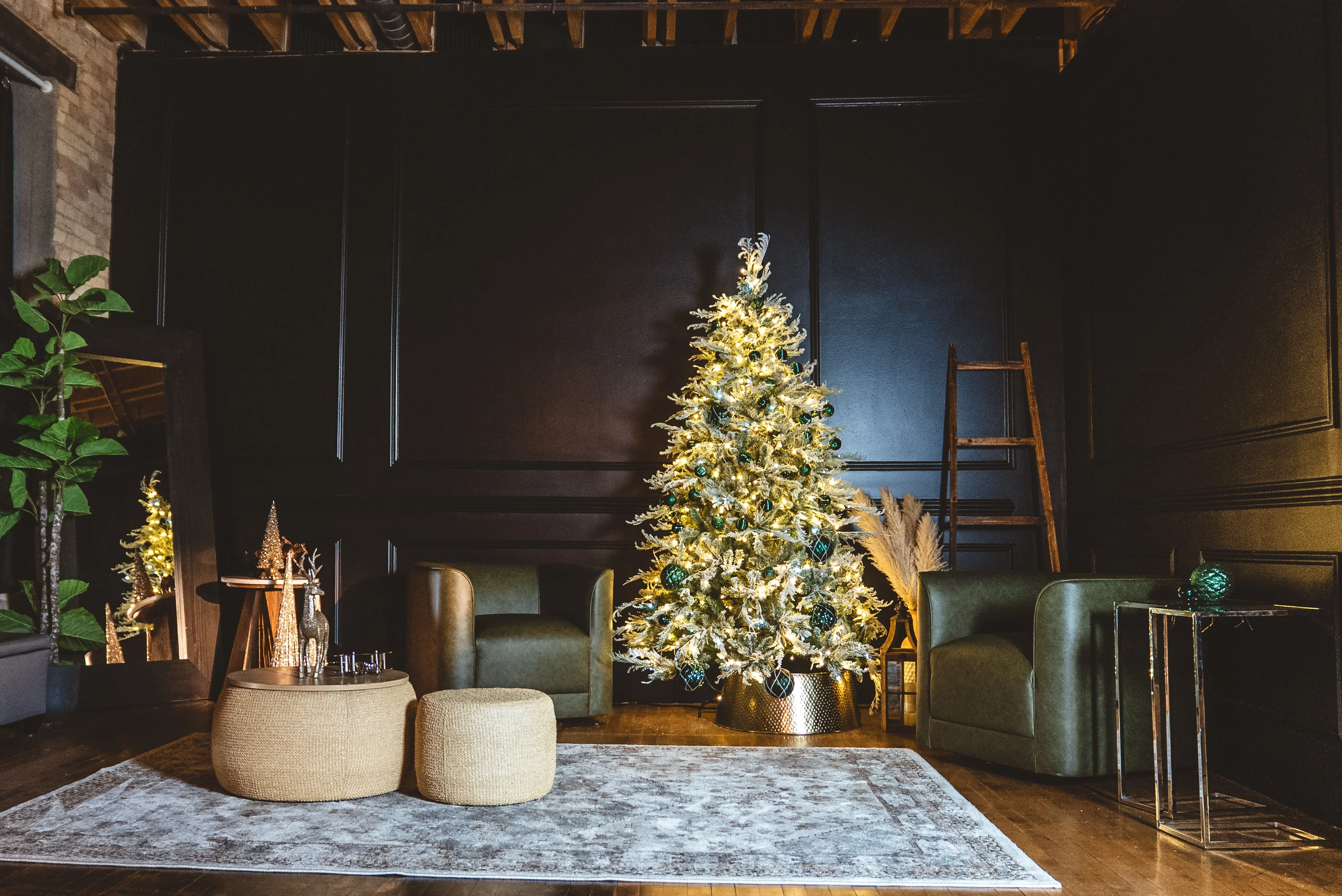 Holiday set with a lit Christmas tree, green armchairs and a rug against a dark wall