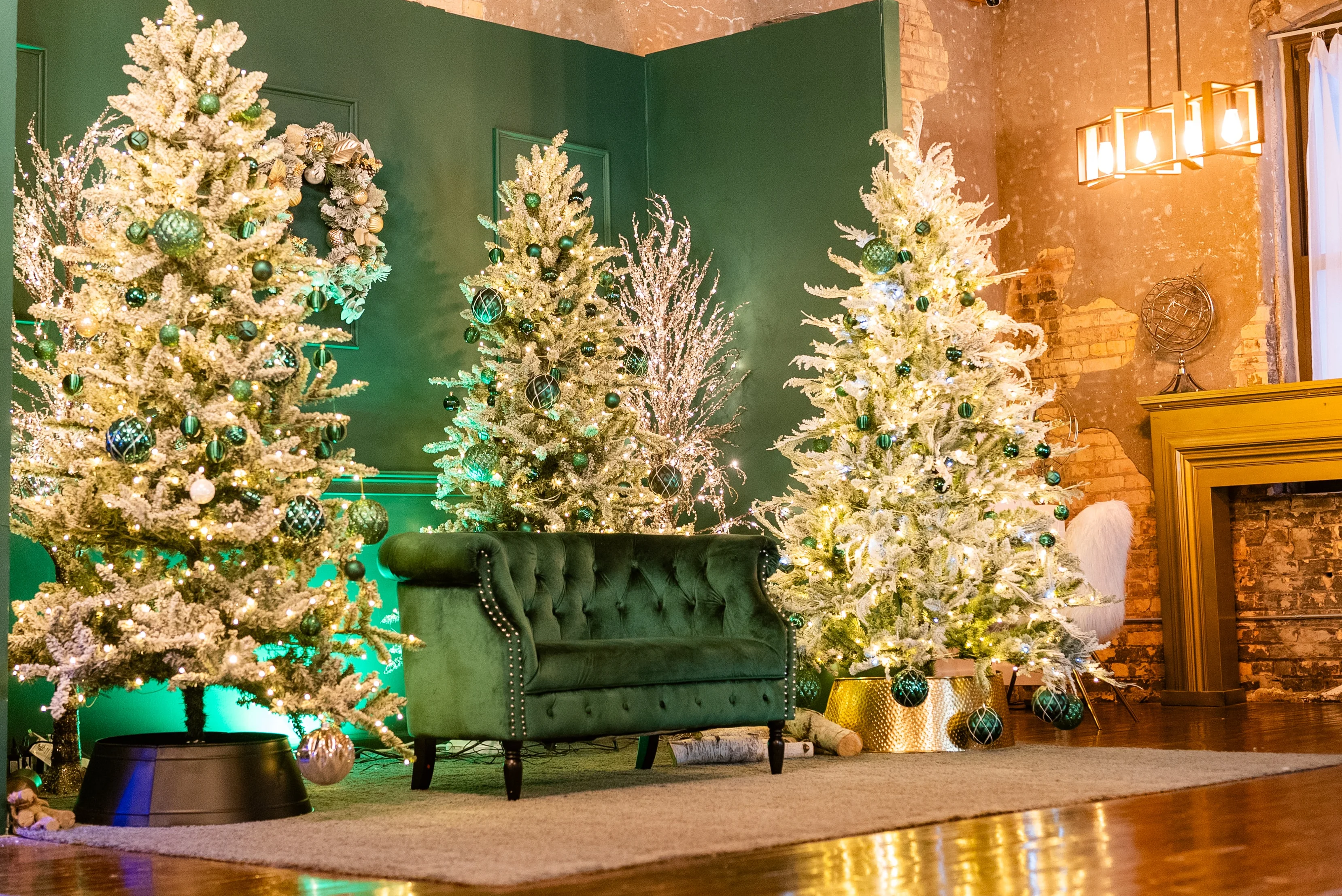 Holiday set with three flocked Christmas trees, a green velvet sofa and a gold fireplace