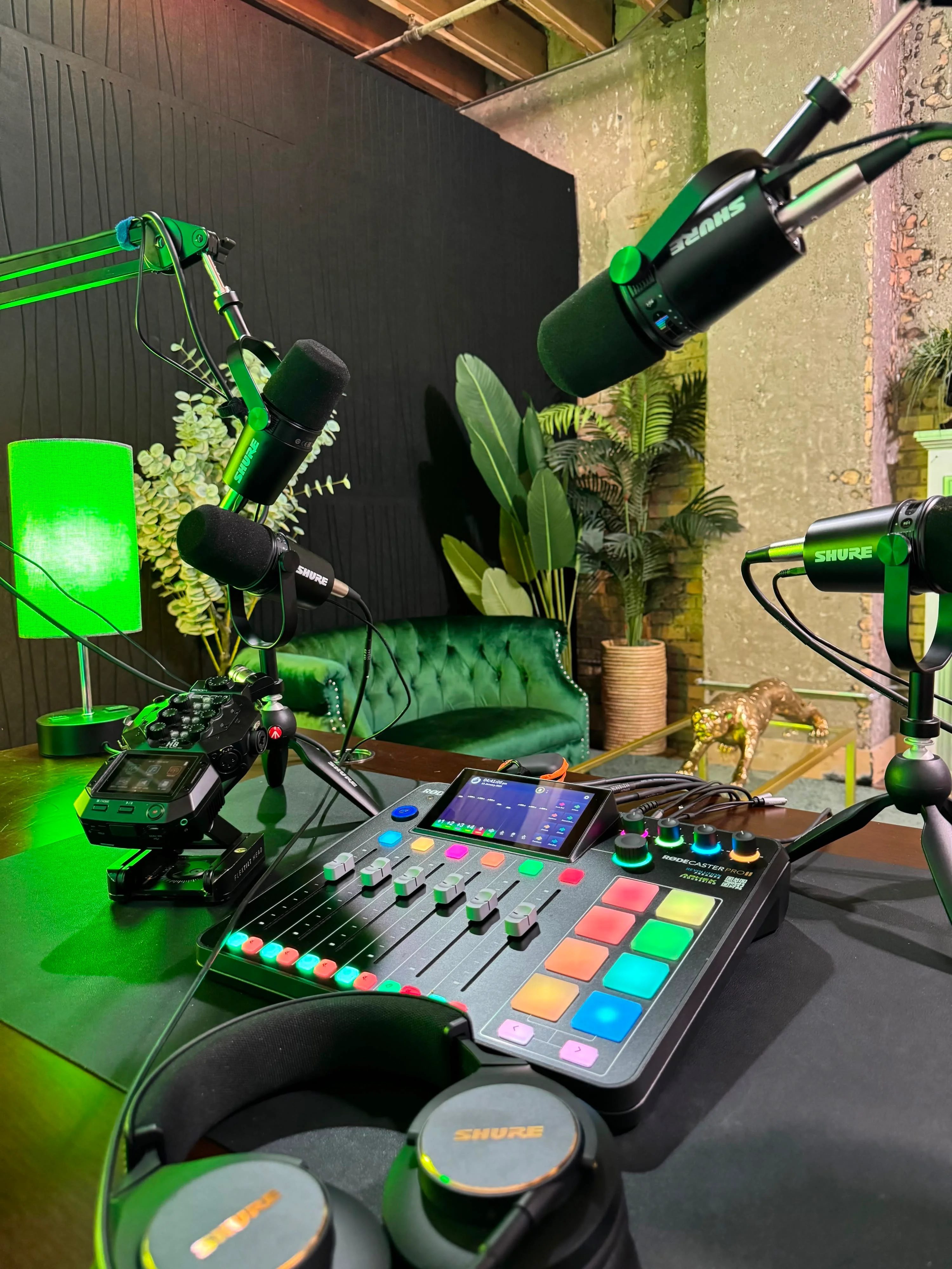 Podcast desk with a mixer and boom microphones under green light