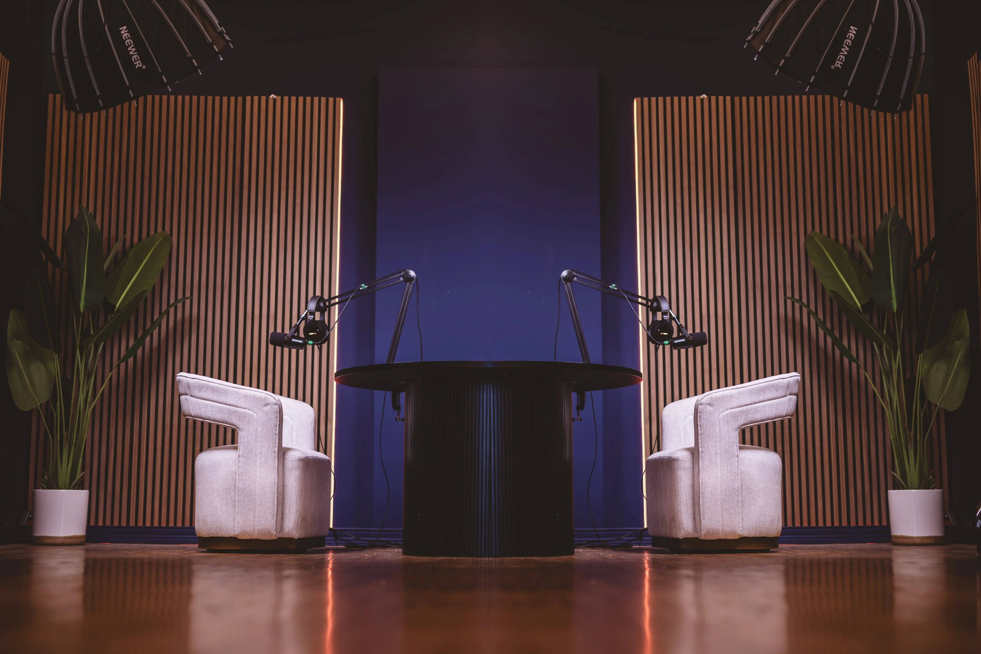 Podcast set with two chairs, boom mics and wood slat walls on navy