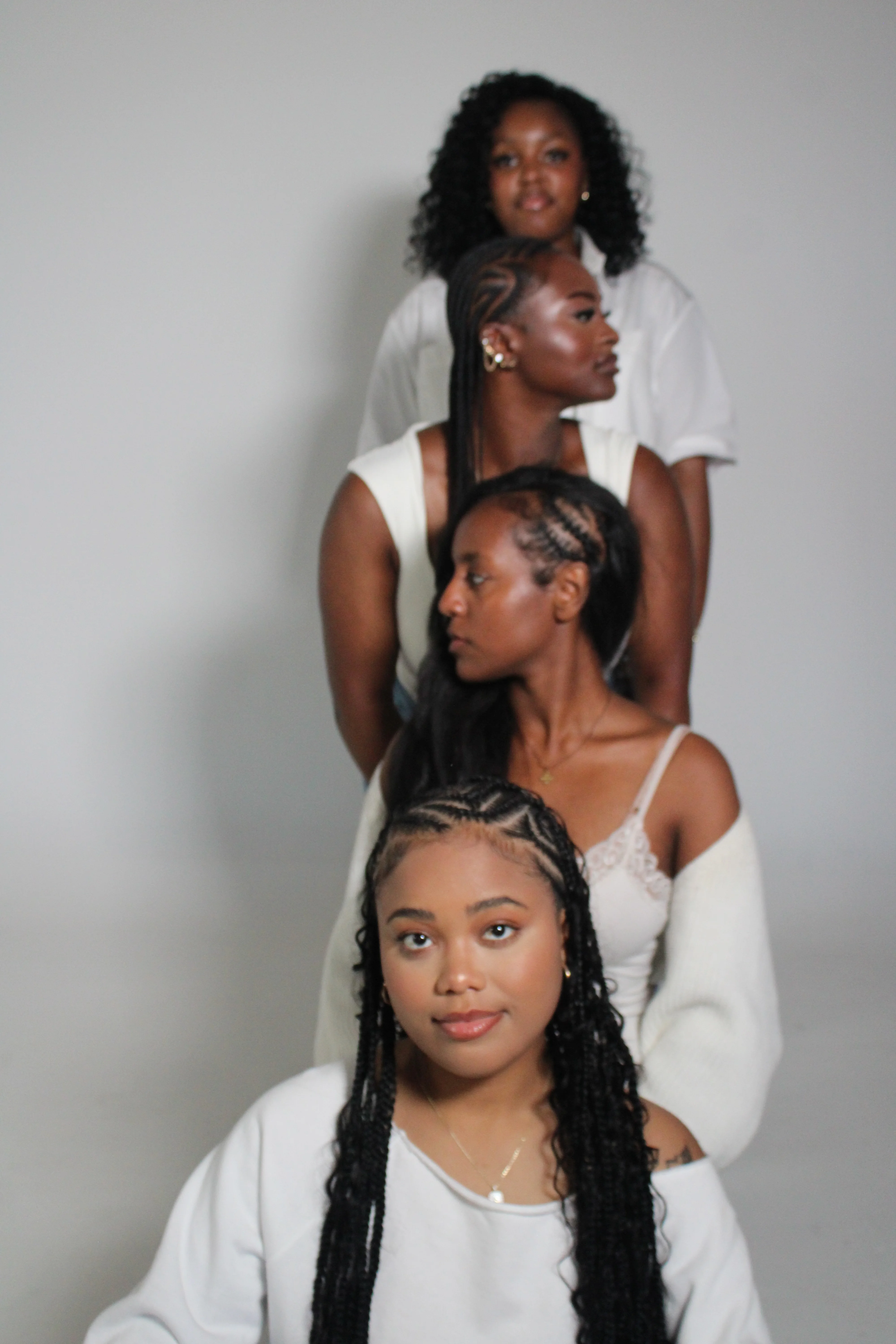 Four women stacked in a vertical group portrait on a light backdrop